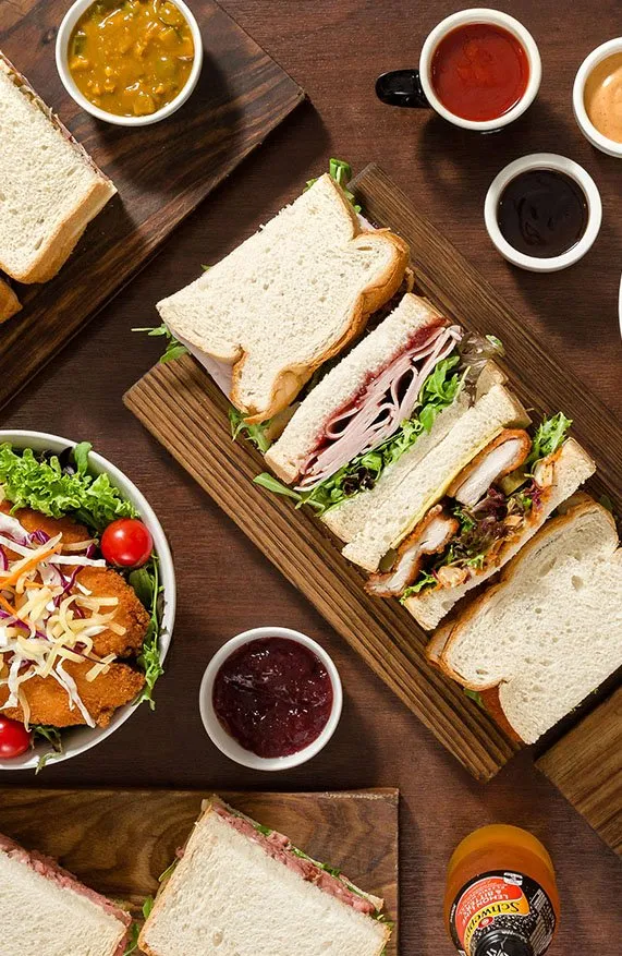 Sandwiches cut in halves and salads on wooden boards, with sauces, at Monty's Sandwich Shop